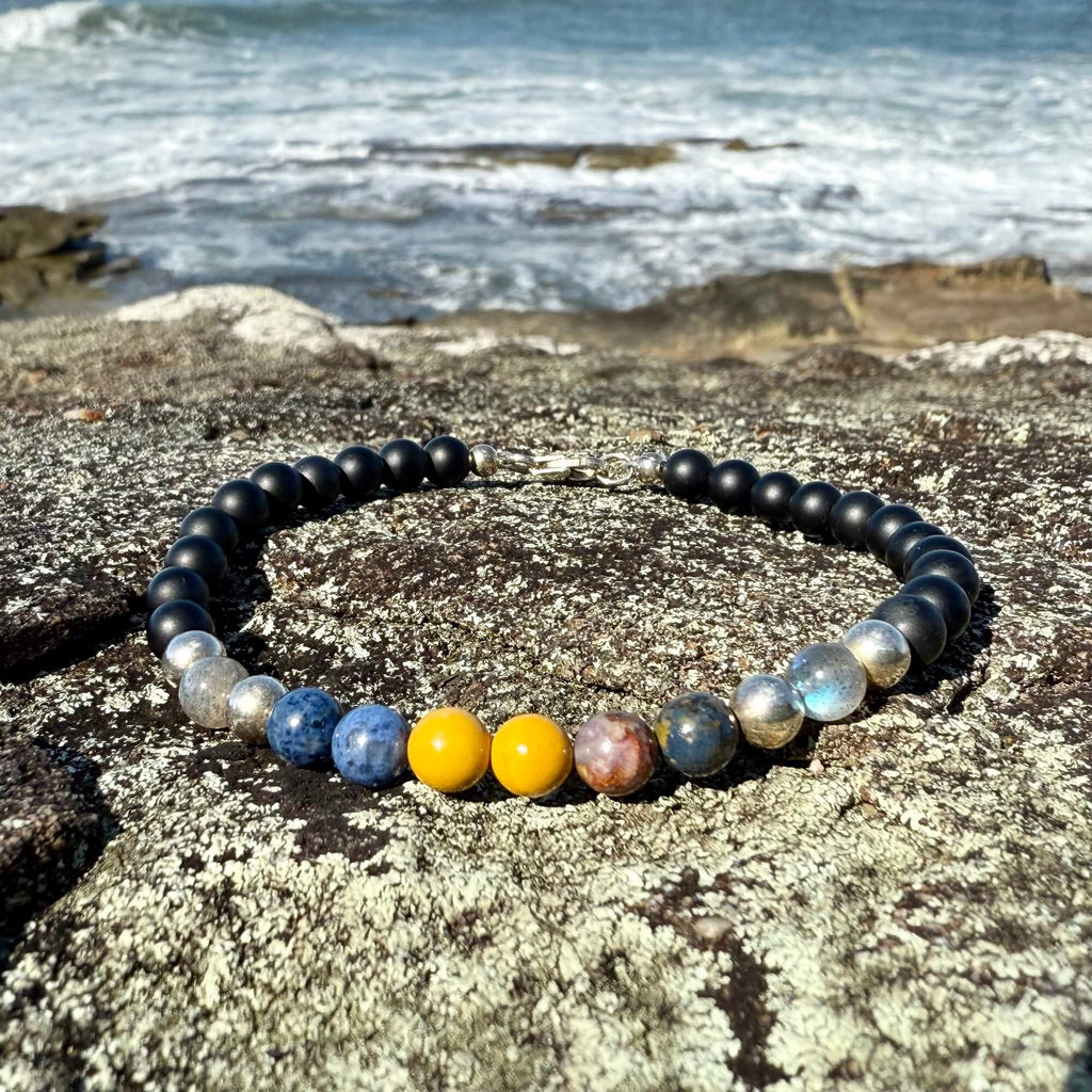 Phoenix Rising bracelet's five-stone centre on a rock by the ocean