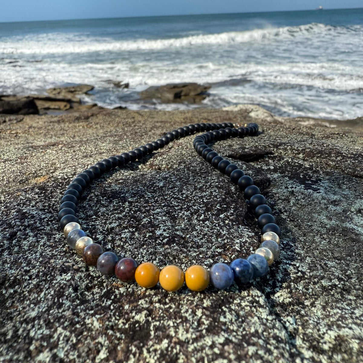 Phoenix Rising men's necklace: black onyx with labradorite, pietersite, dumortierite and mookaite, on coastal rock