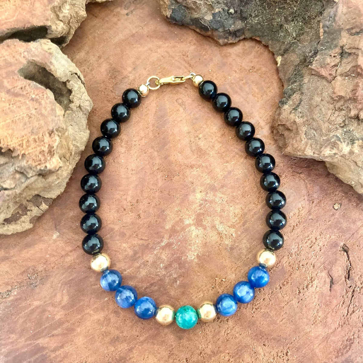 The Alchemist bracelet laid lengthwise on rock, showing the kyanite and chrysocolla