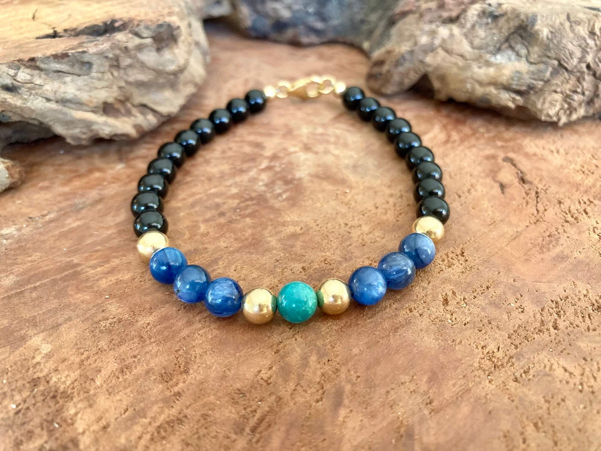 The Alchemist bracelet resting on rock, gold-fill clasp at the back