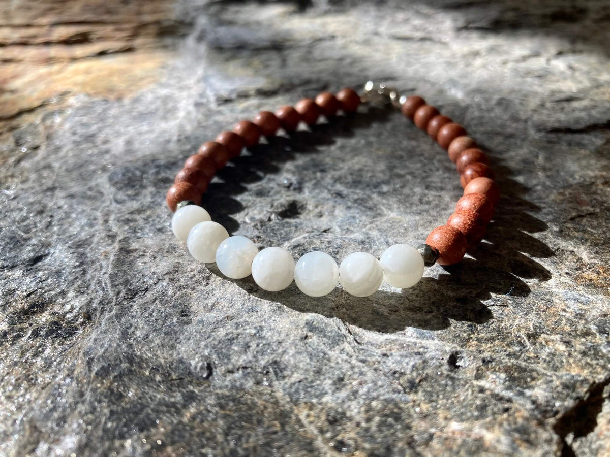 Balance moonstone bracelet on lichen-covered rock in soft light