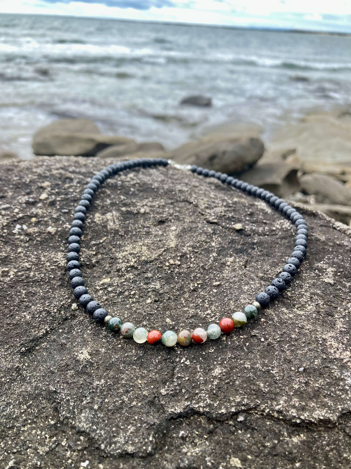 Bloodstone section of the Strength necklace on dark rock