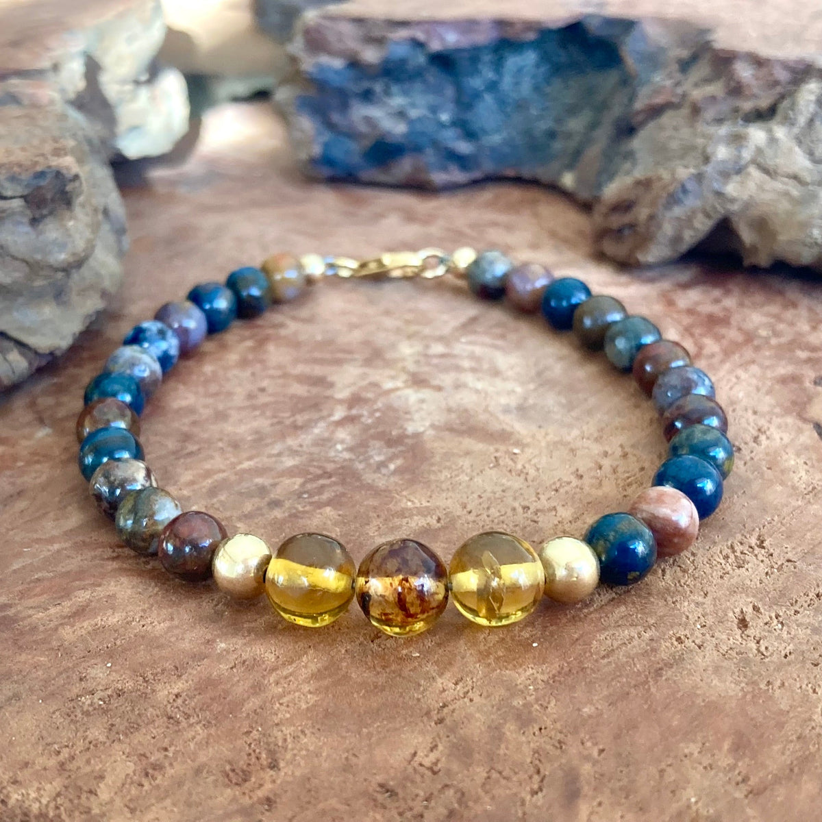 The Catalyst men's bracelet: blue-gold pietersite with Mexican Chiapas amber and 14k gold-fill beads, on wood