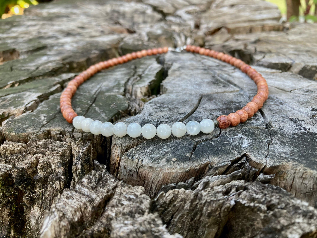 Close-up of the Balance necklace's moonstone beads on weathered wood