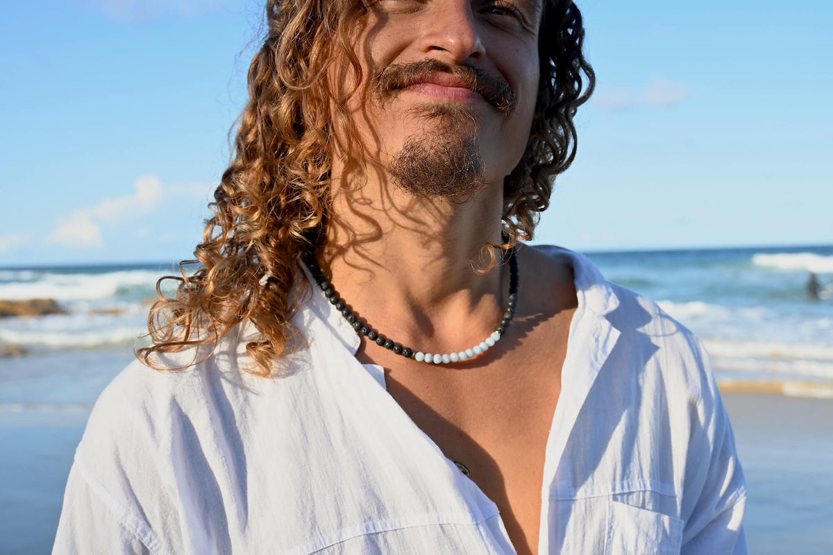 Close-up of a man at the beach wearing the Courage aquamarine necklace