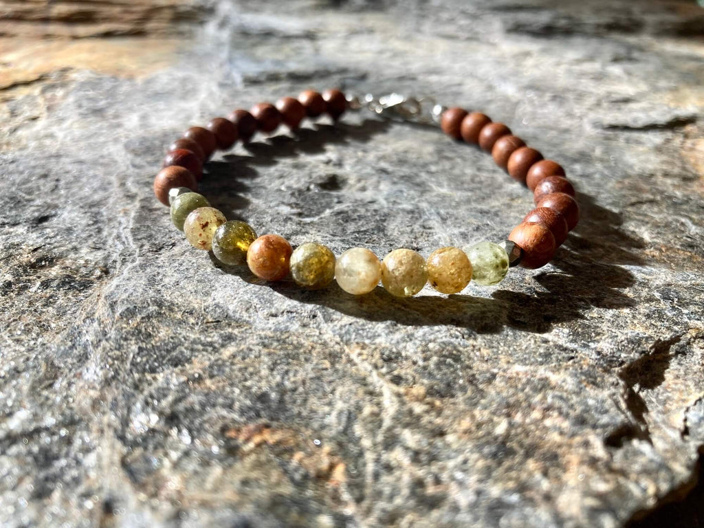 Close-up of olive-green garnet beads on the Growth bracelet, on stone