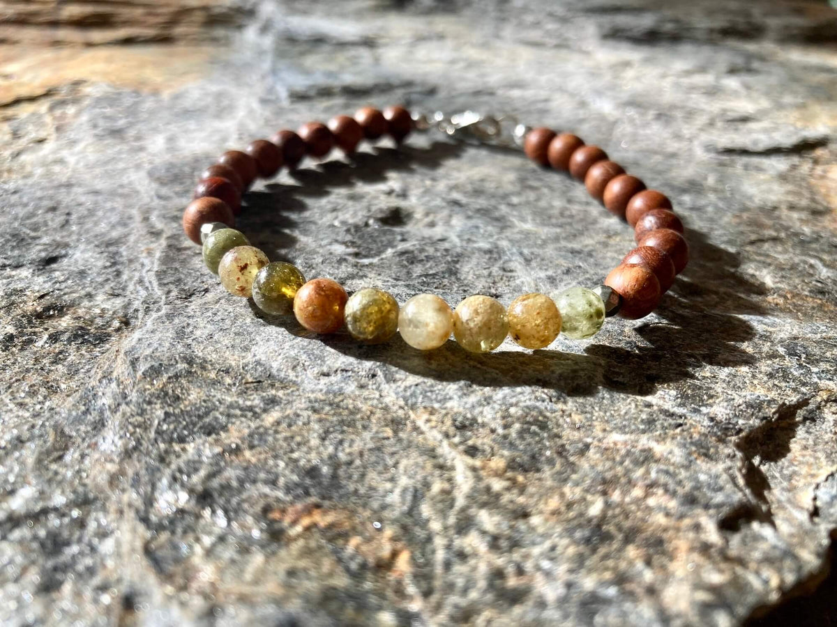 Close-up of olive-green garnet beads on the Growth bracelet, on stone