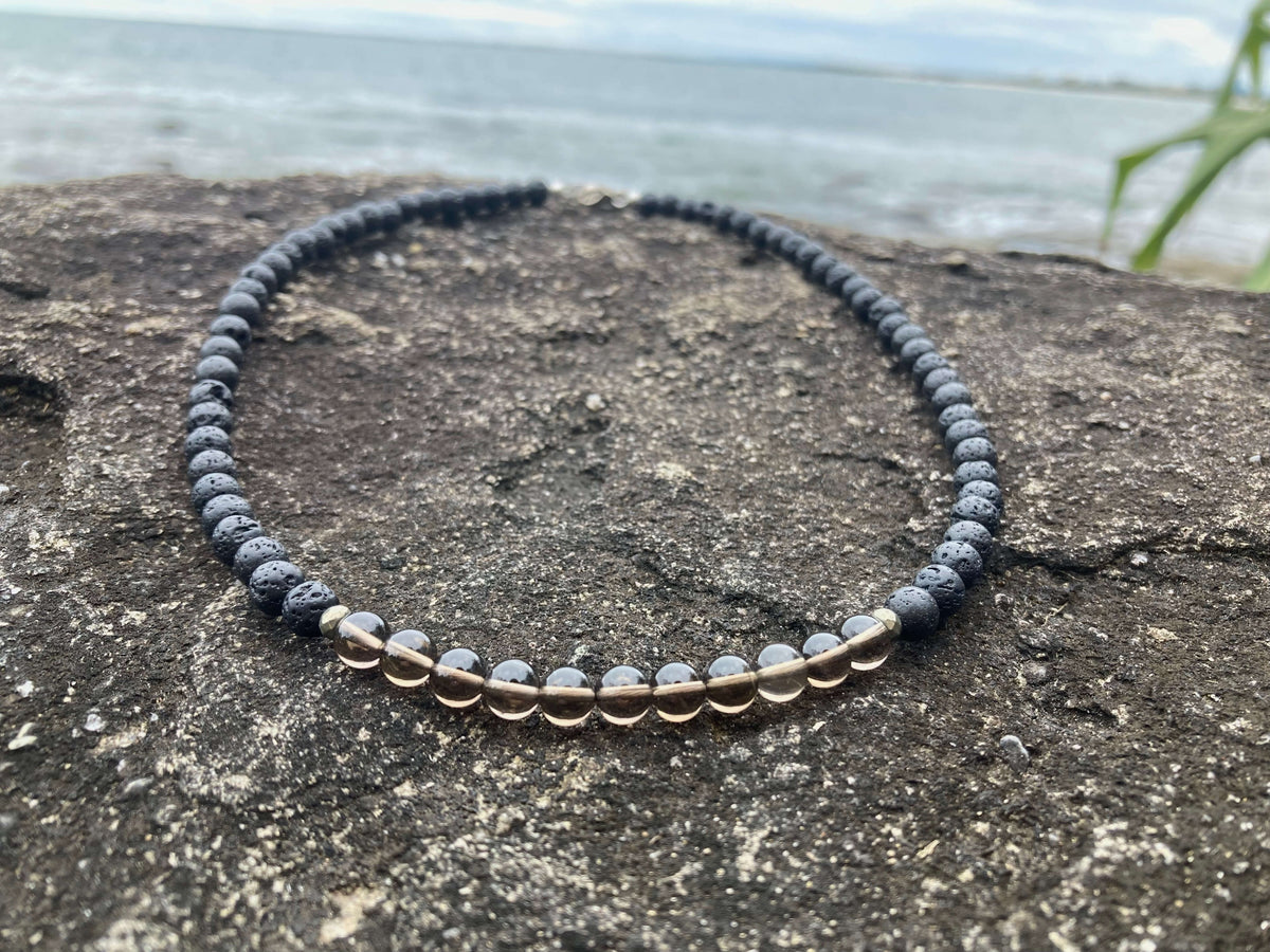 Close-up of the Self-Assurance necklace's smoky quartz beads on rock