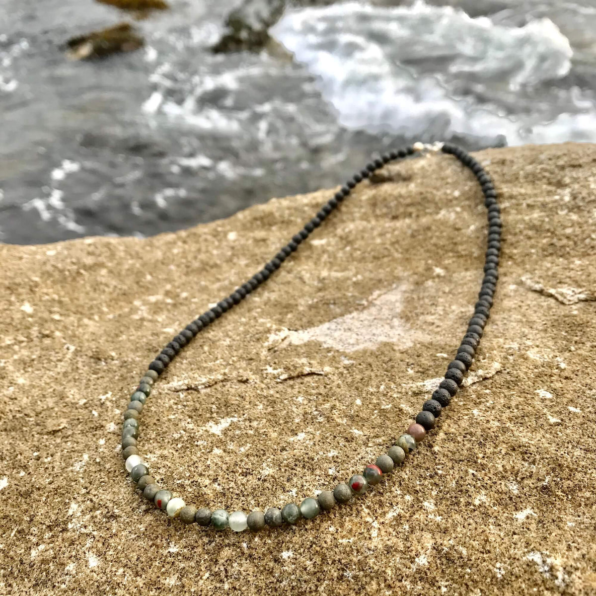 Conviction bloodstone and pyrite necklace on a sandstone rock