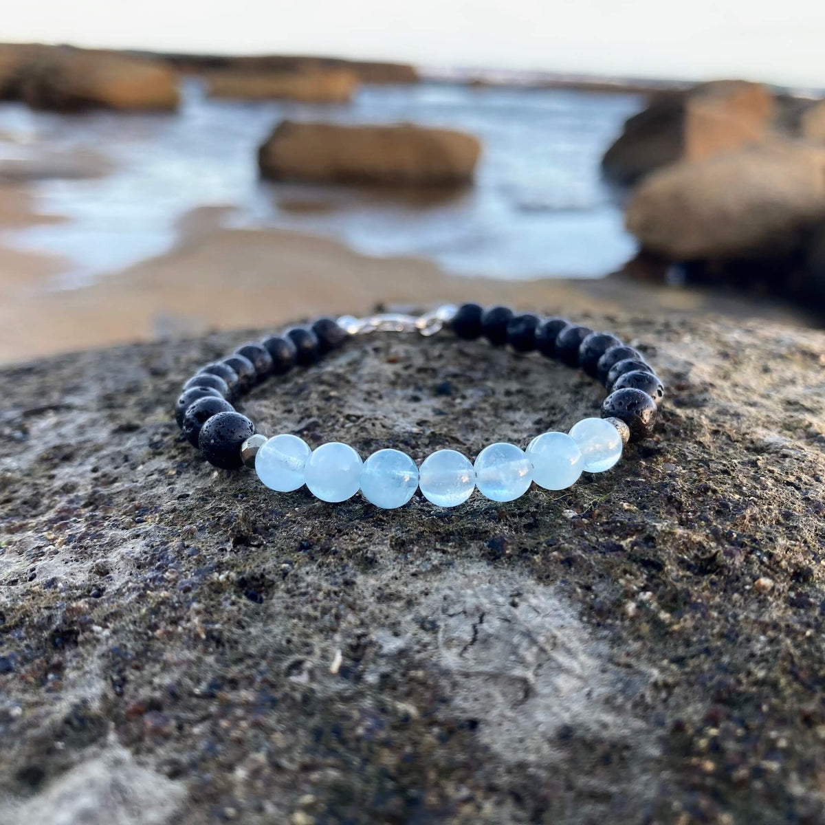 Courage aquamarine bracelet on dark rock with rock pools behind