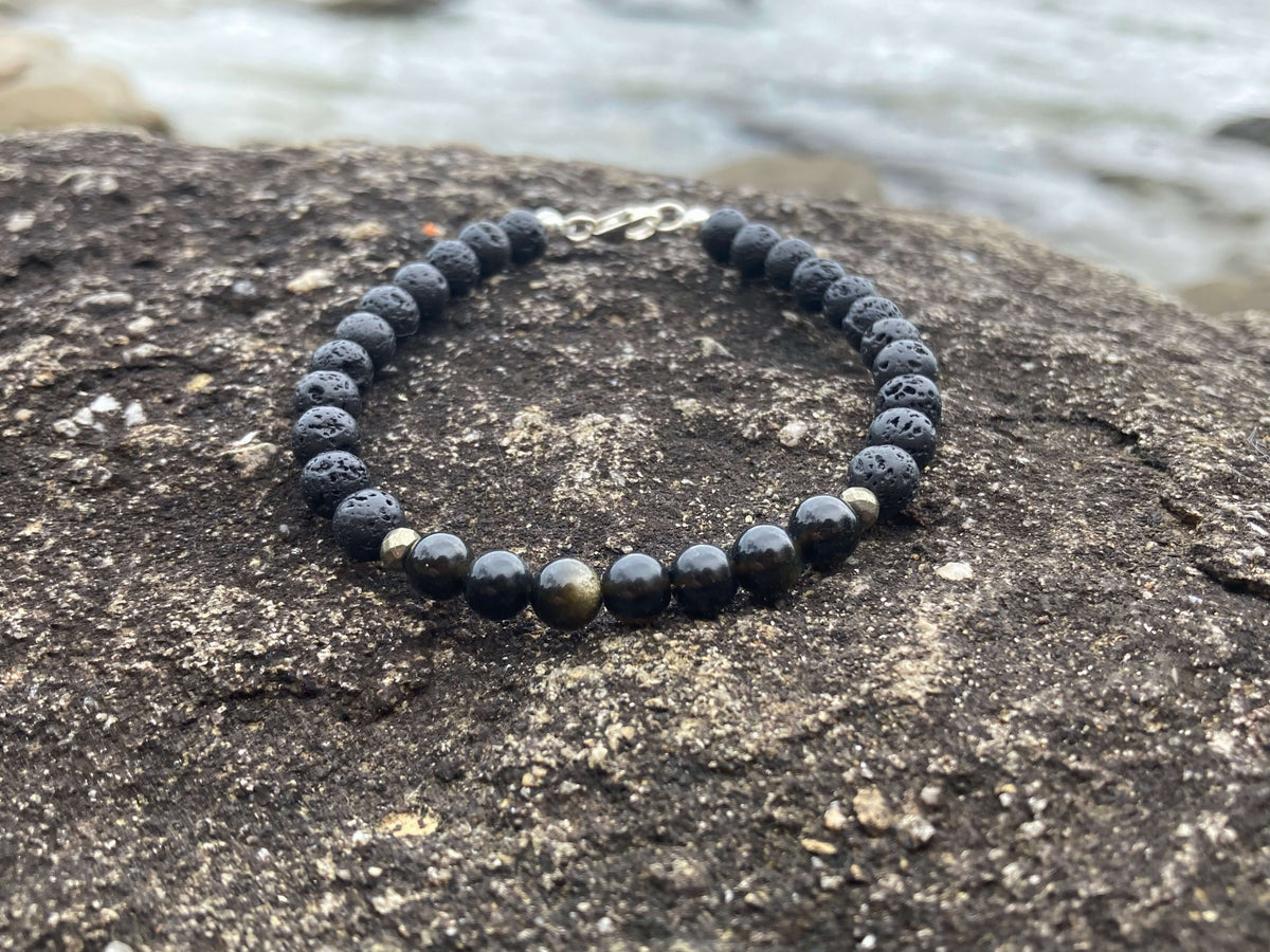 Facing Fears bracelet on dark rock with the shoreline blurred behind