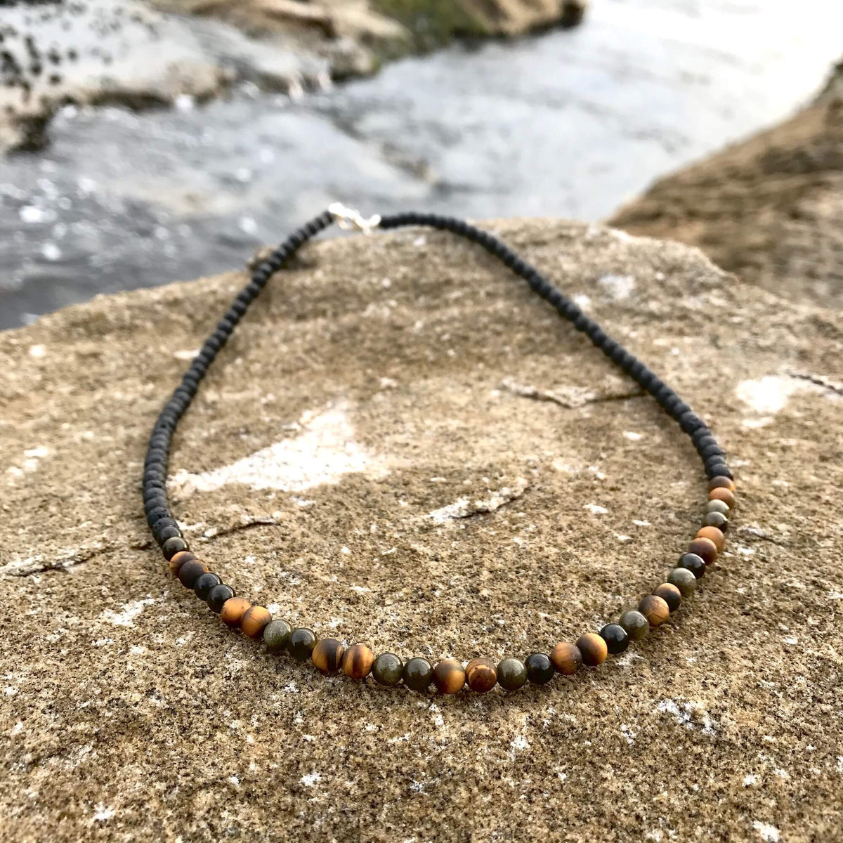 Fortitude necklace's tiger's eye section on a sandstone rock