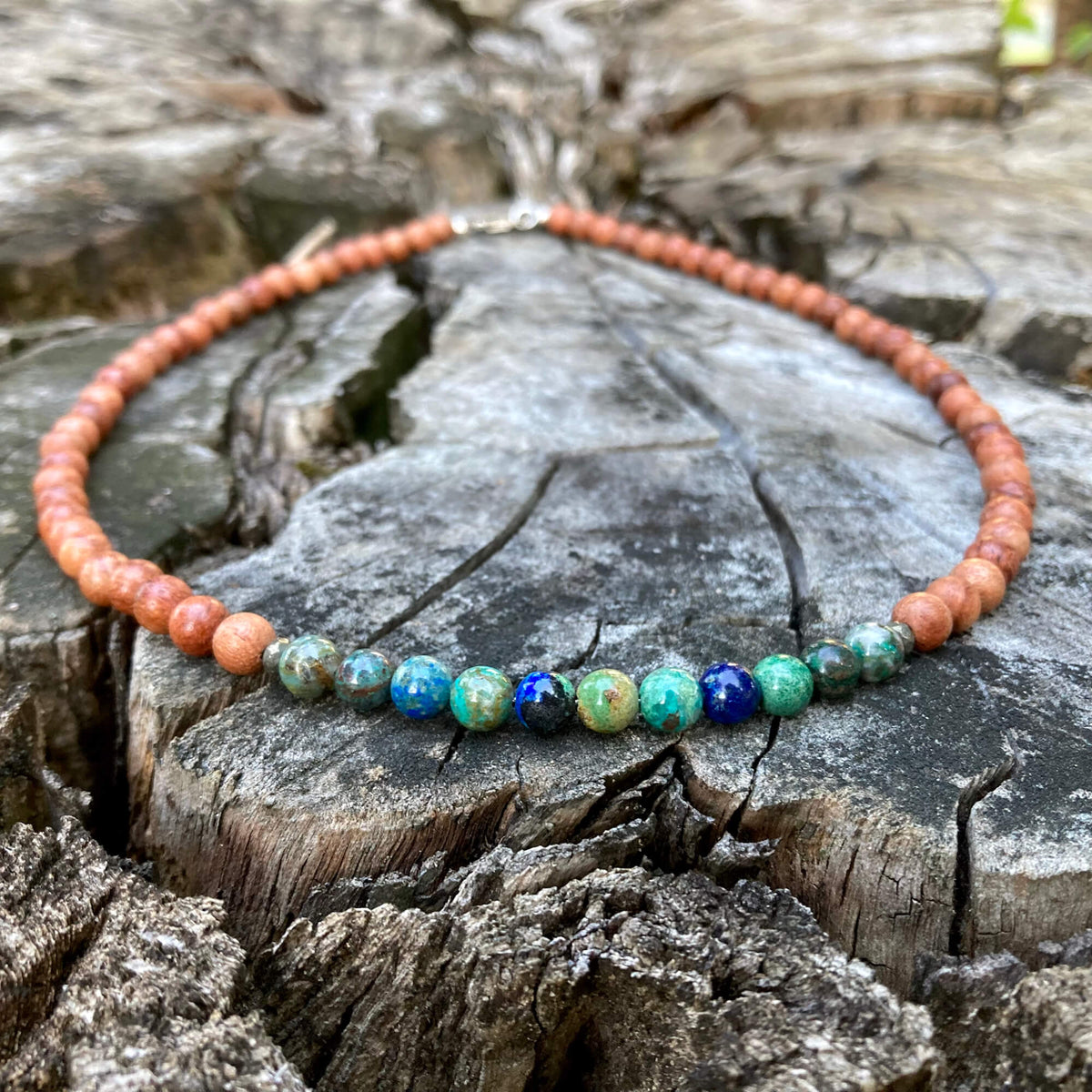 Inner Wisdom men's necklace: azurite with natural wood beads, laid on a weathered stump
