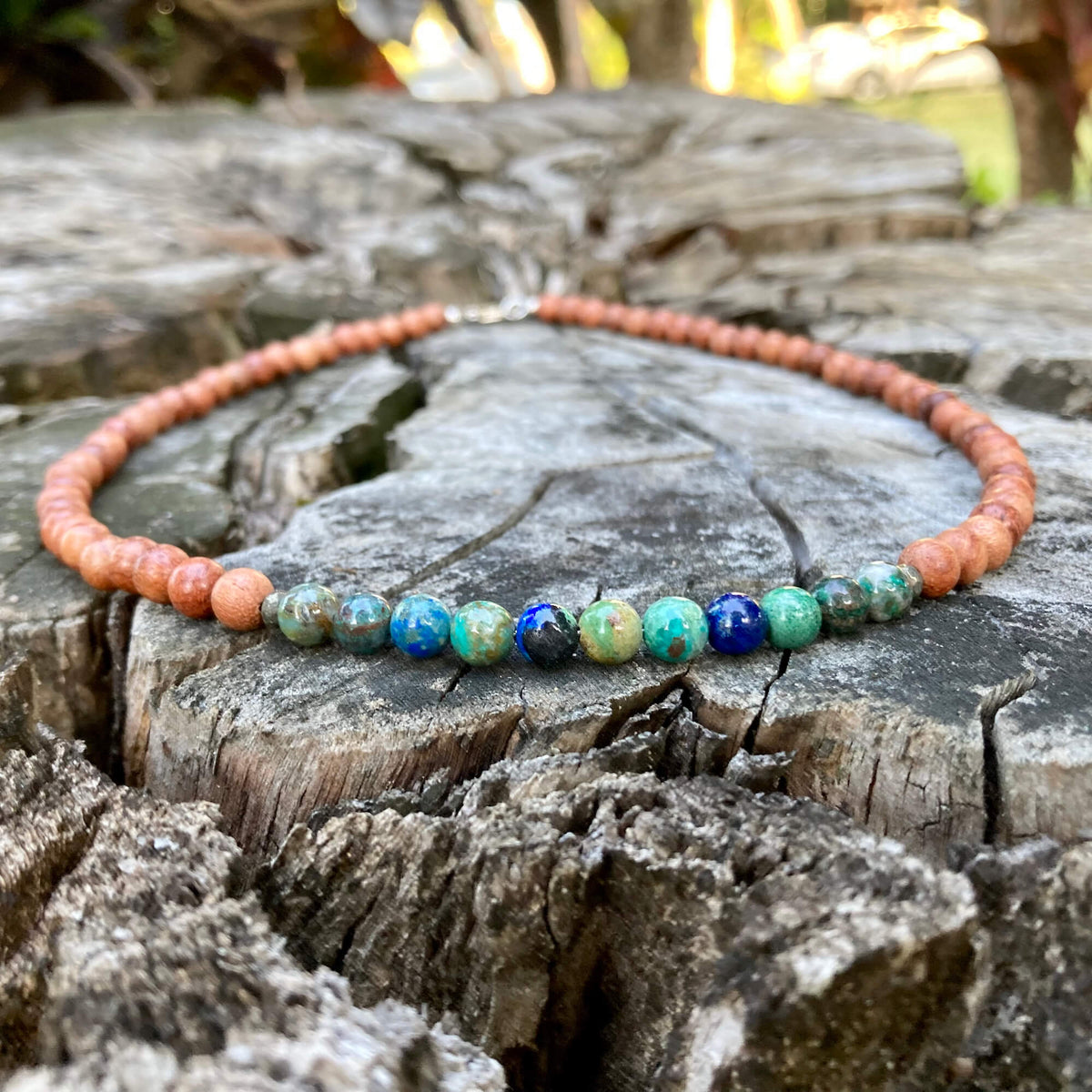 Inner Wisdom necklace's azurite section across a cracked tree stump