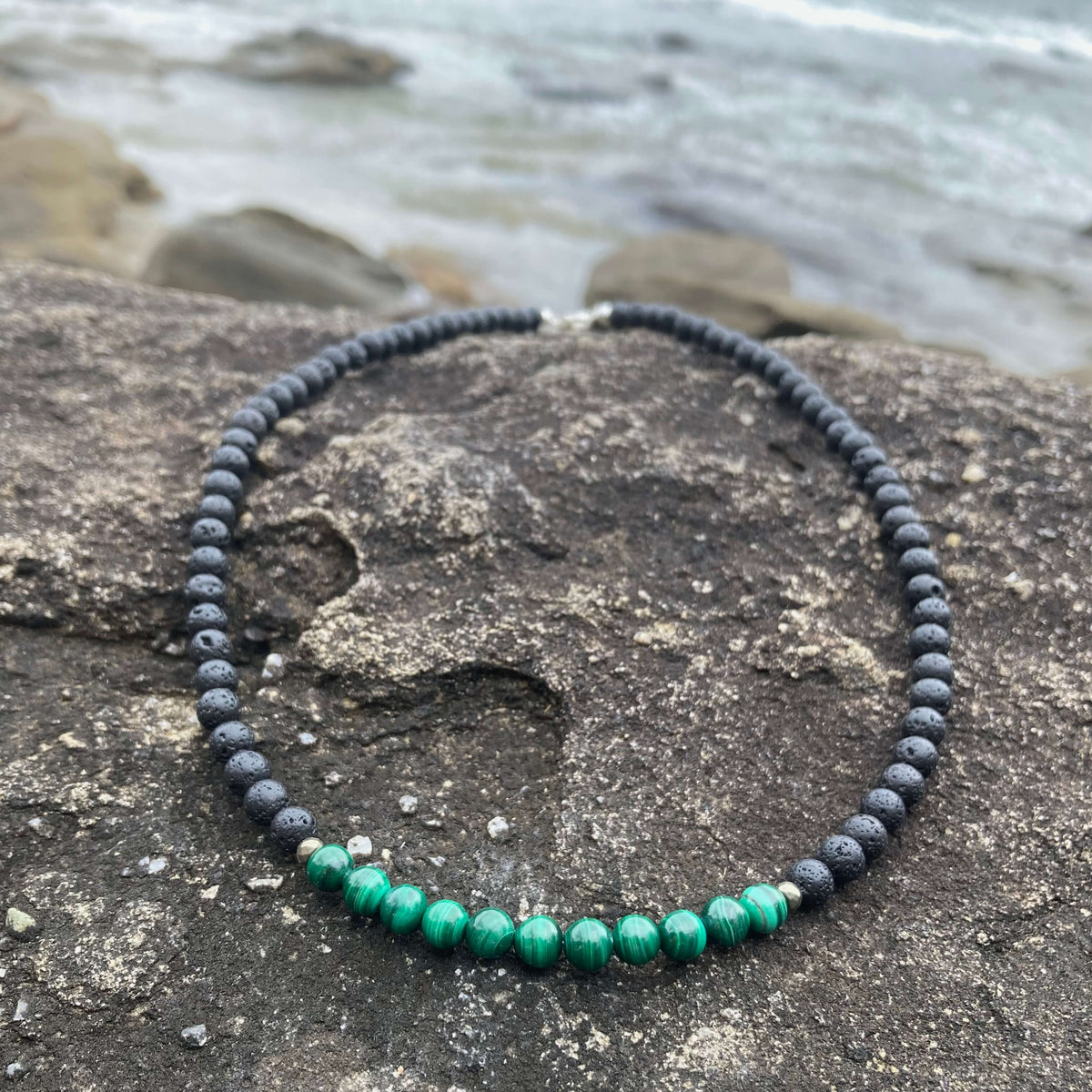 Malachite section of the Manifestation necklace on dark rock