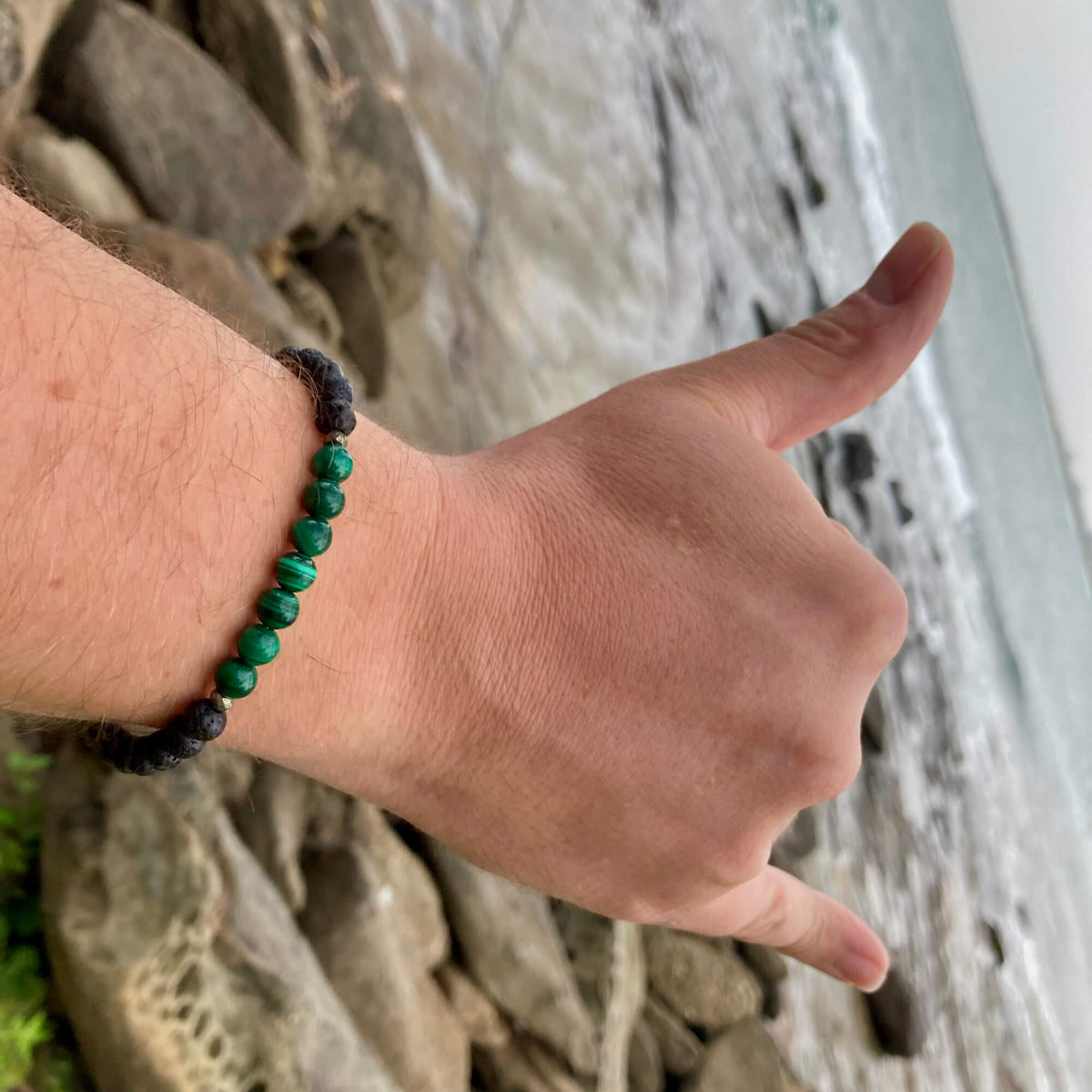 Man giving a shaka by a cliff, wearing the Manifestation bracelet