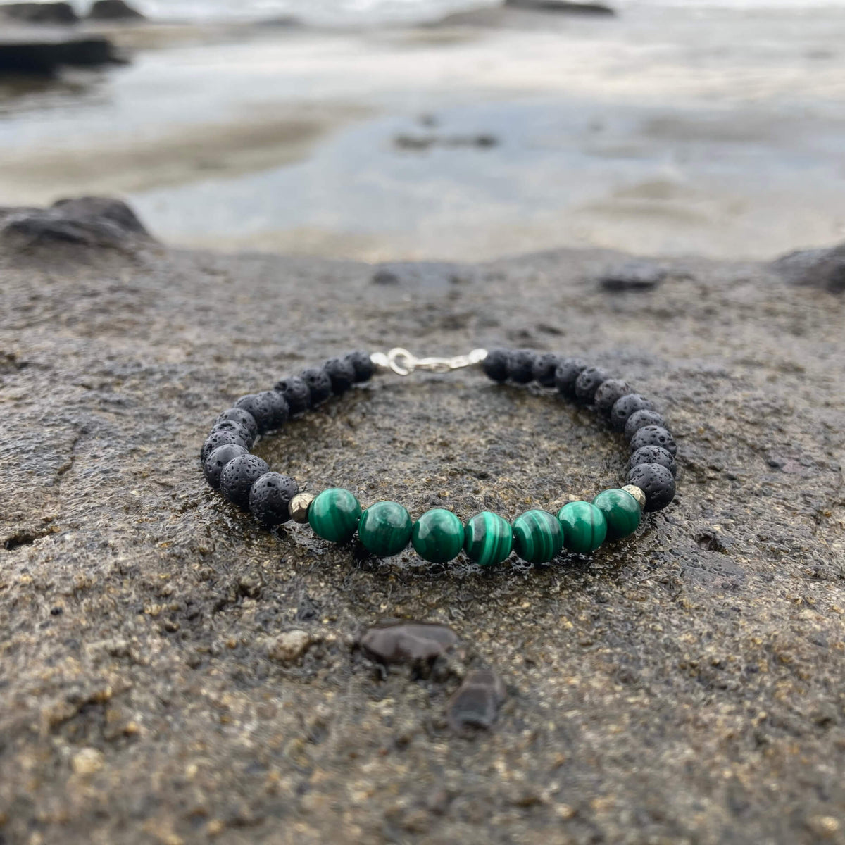Manifestation malachite bracelet on dark rock, seen from a low angle