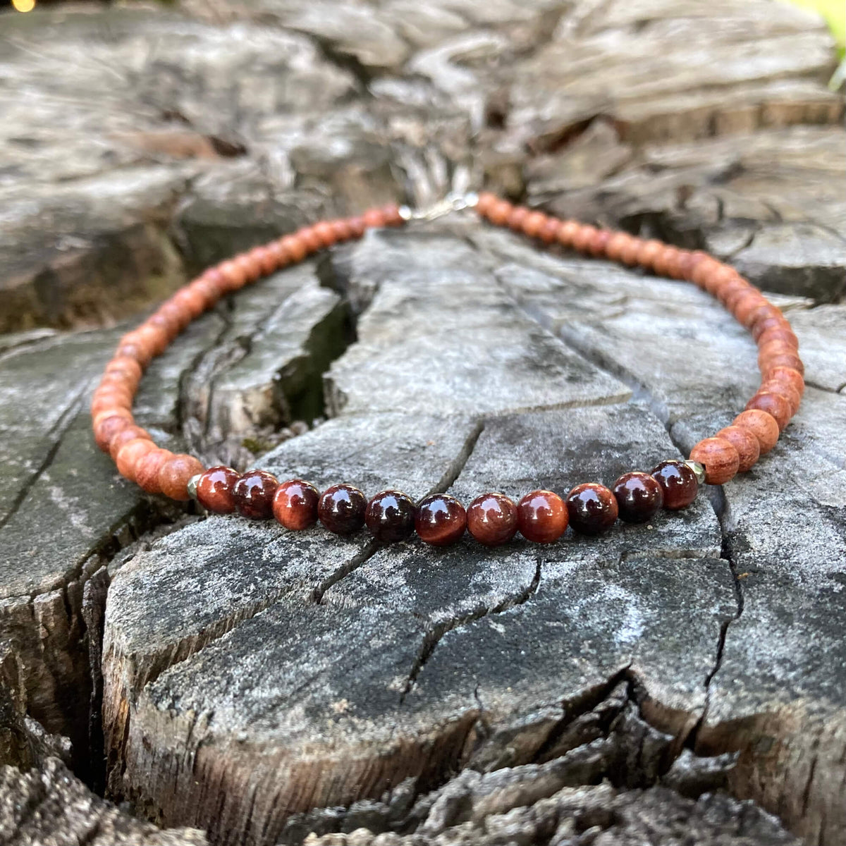 Motivation men's necklace: red tiger's eye with natural wood beads, laid on a weathered stump