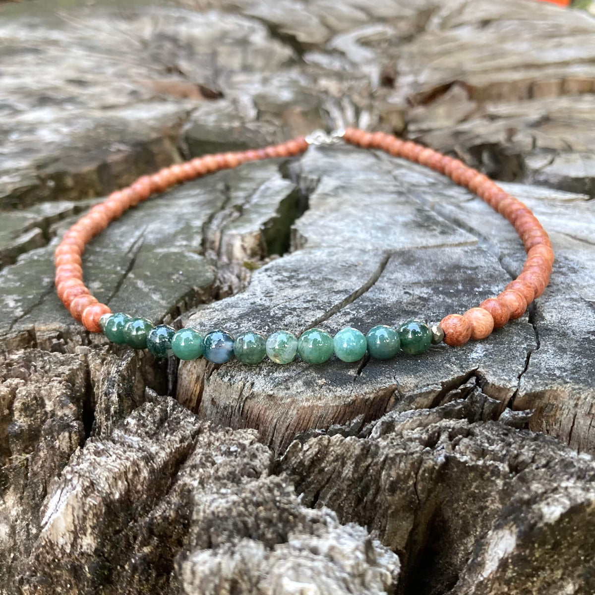 New Beginnings men's necklace: green moss agate with natural wood beads, laid on a weathered stump