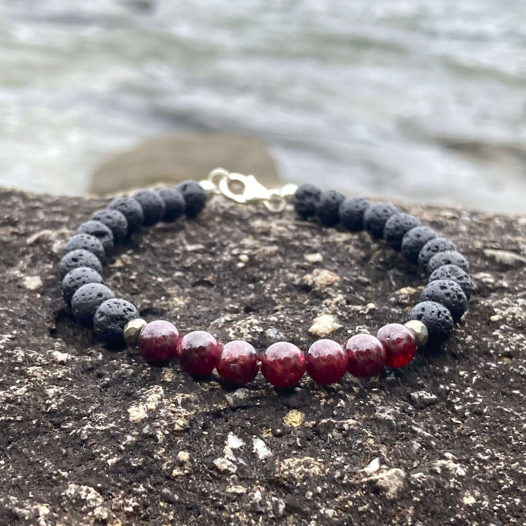 Prosperity garnet bracelet on dark rock with the sea behind