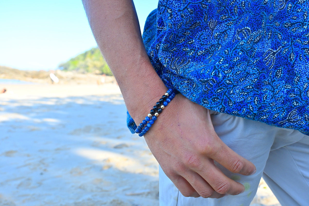 The Seeker bracelet worn on a man's wrist at the beach