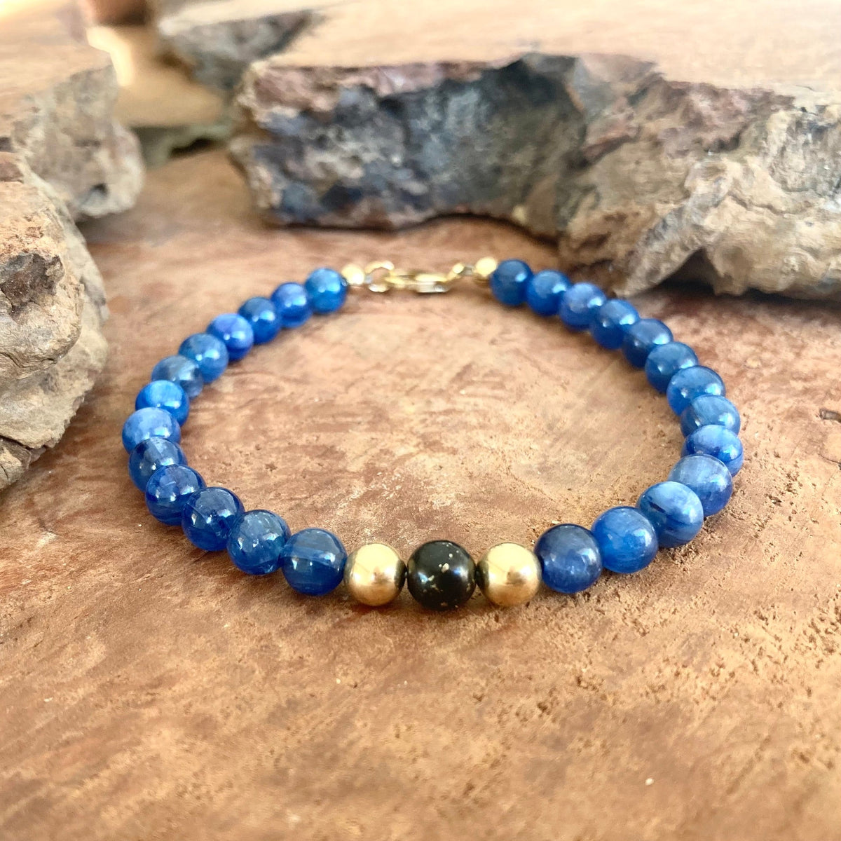 The Seeker men's bracelet: blue kyanite beads, two 14k gold-fill beads and a black shungite centre bead, on driftwood