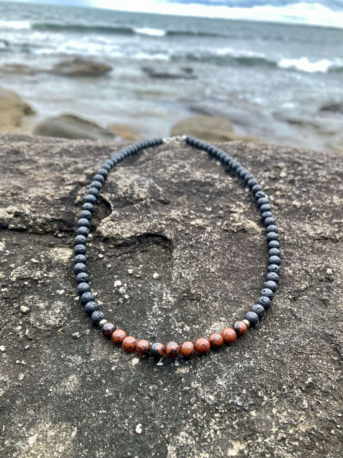 Self-Acceptance necklace on coastal rock, seen from further back
