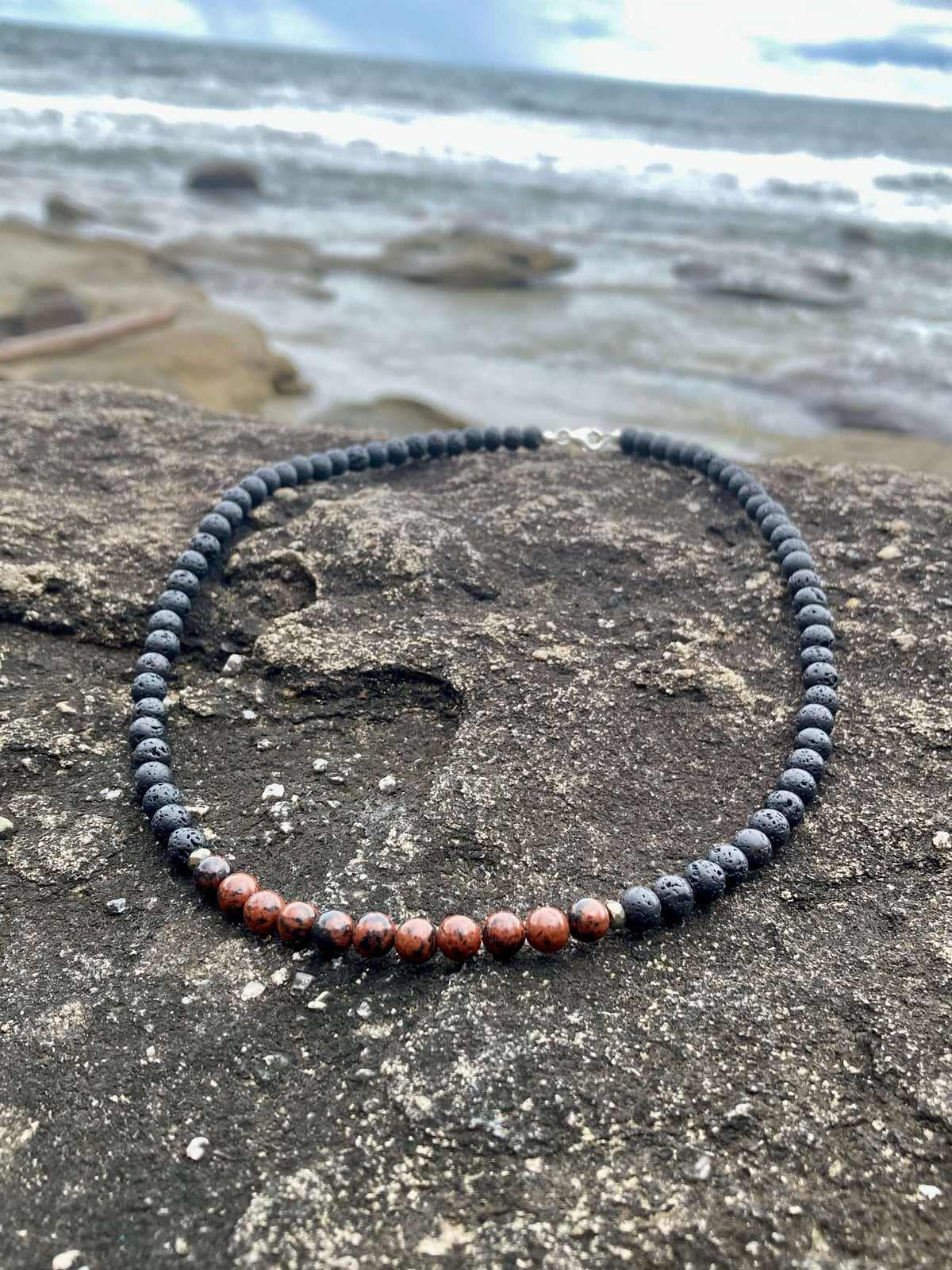 Self-Acceptance necklace on a rock with waves behind