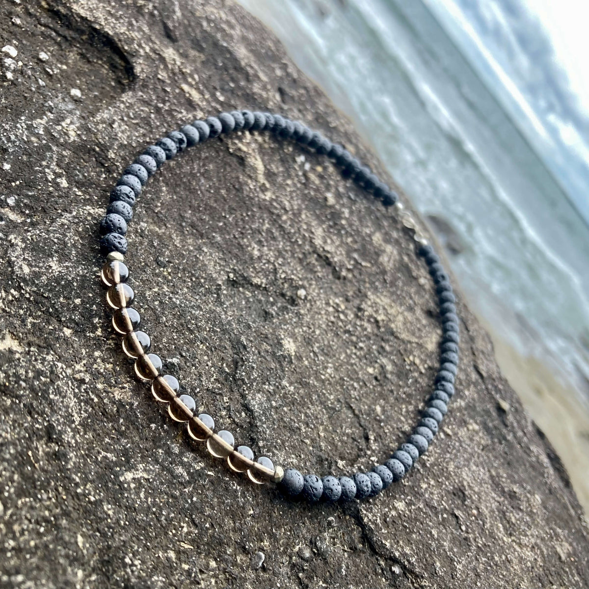 Self-Assurance necklace draped on a sloping rock, smoky quartz in focus
