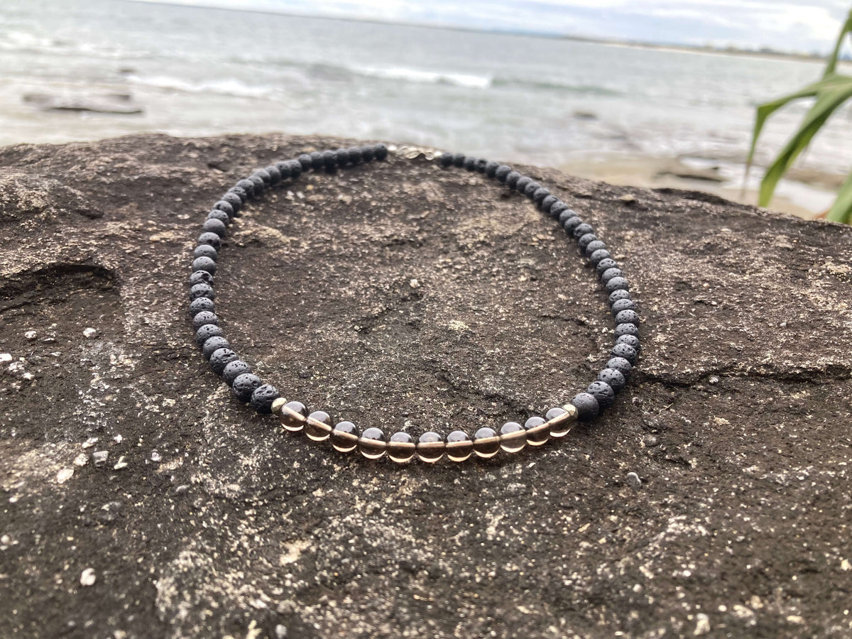 Self-Assurance necklace on a rock with the beach and sea behind