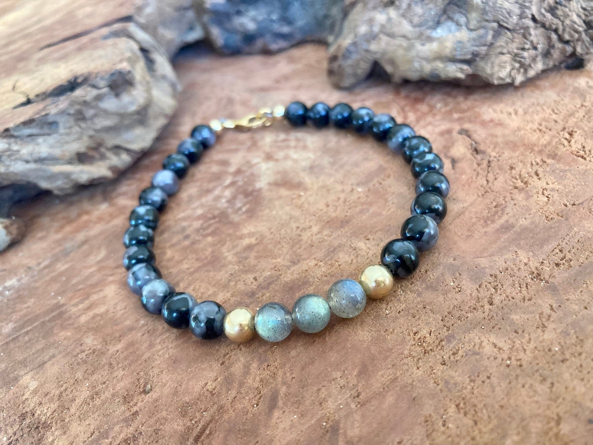 The Shadow Walker bracelet on a timber slab with rocks behind