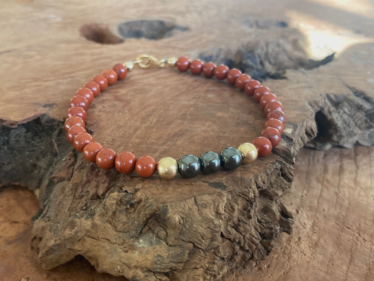 The Steadfast bracelet draped over driftwood, hematite beads at the front