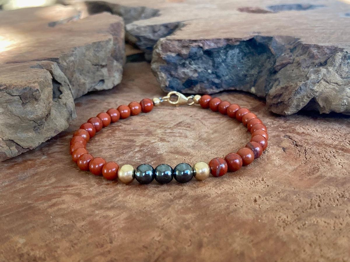 The Steadfast bracelet on a timber slab beside rock, seen from further back