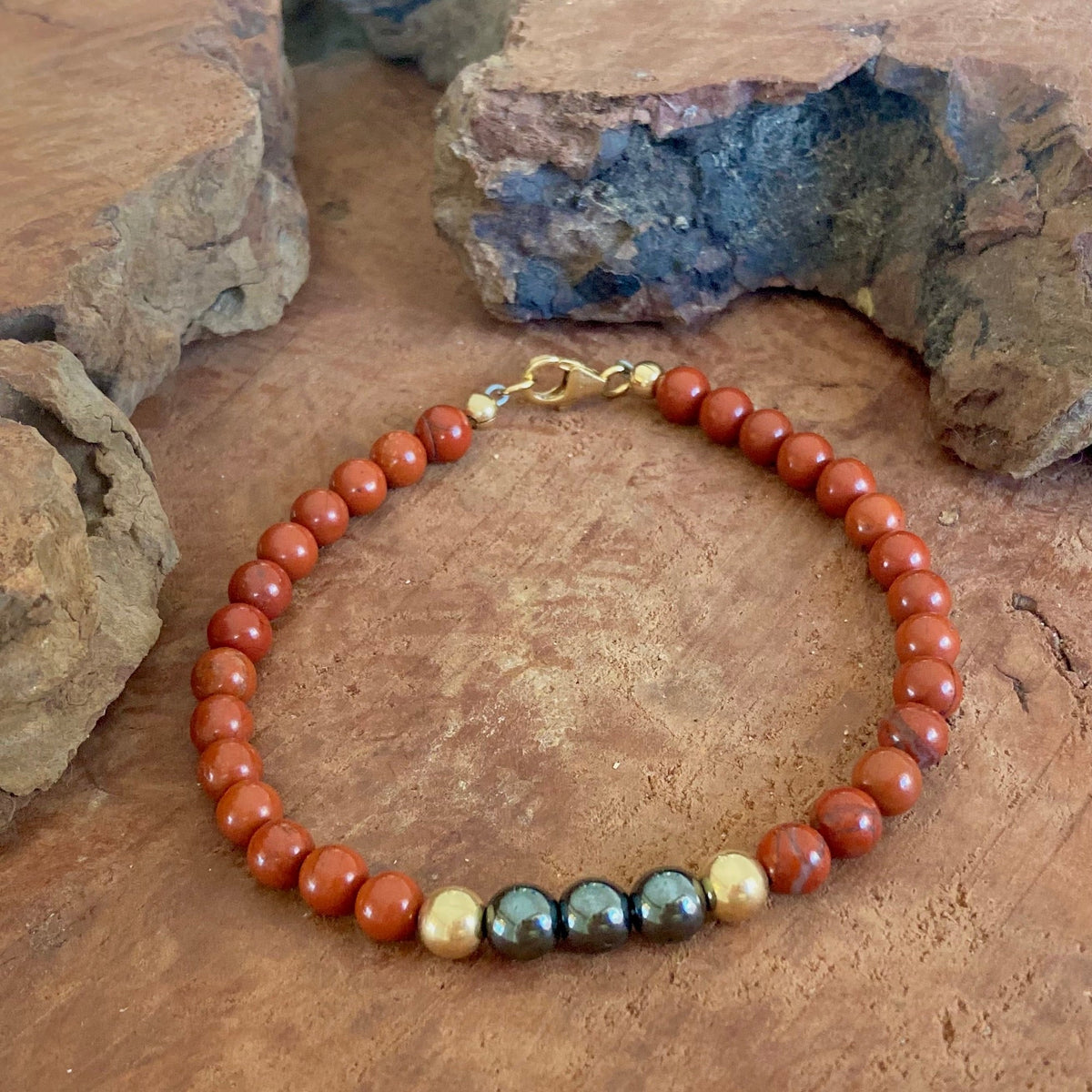 The Steadfast men's bracelet: red jasper with silver-grey hematite and 14k gold-fill beads, on wood