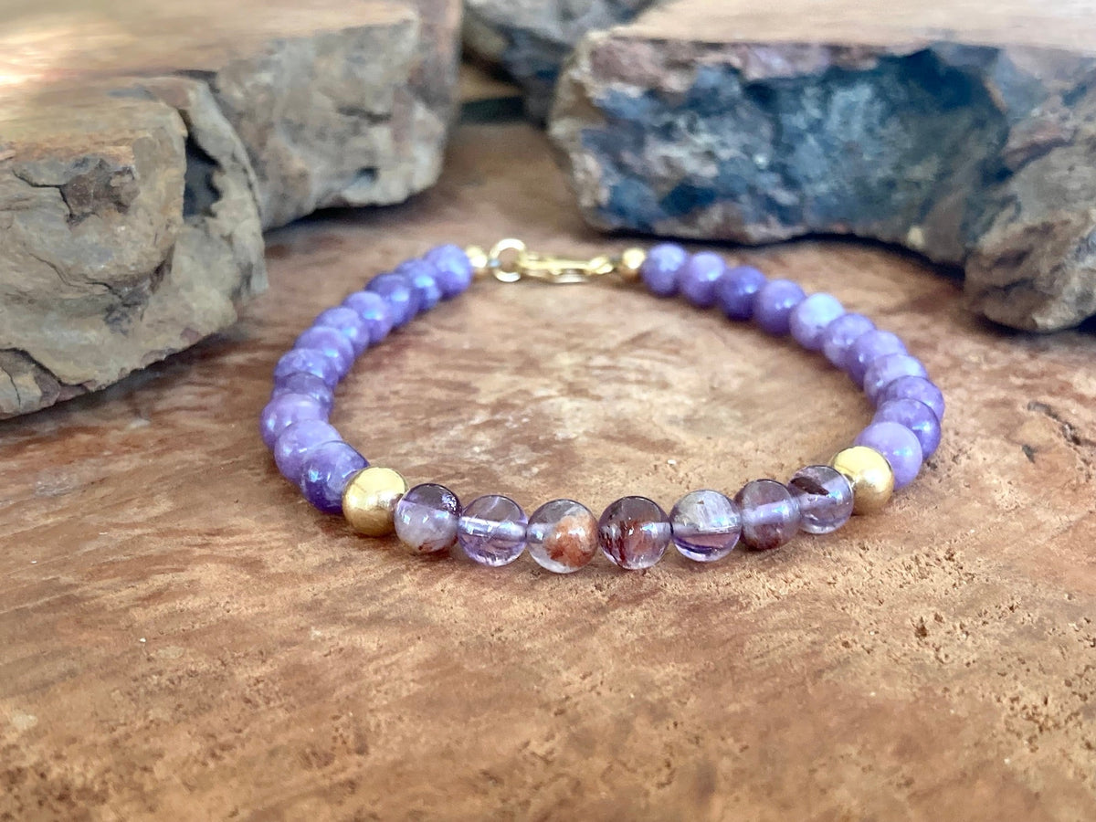 The Visionary bracelet on a wooden slab with rocks behind